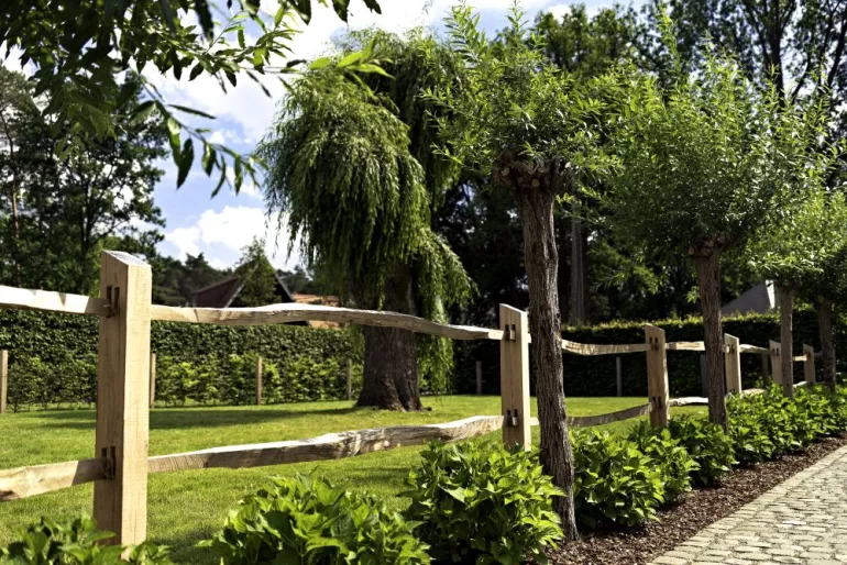 Ein Zaun aus gespaltener Kastanie mit quadratischen Pfosten und 2 Stäben in einem Garten