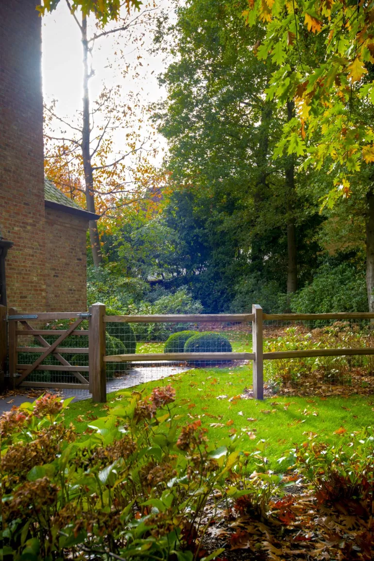 Ein gespaltener Kastanienzaun mit 2 Stäben und einem Maschendrahtzaun darauf, der an einem Holztor befestigt ist