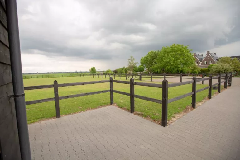 Schwarzer Holzzaun mit schwarzen Vierkantpfosten und einem Feldtor