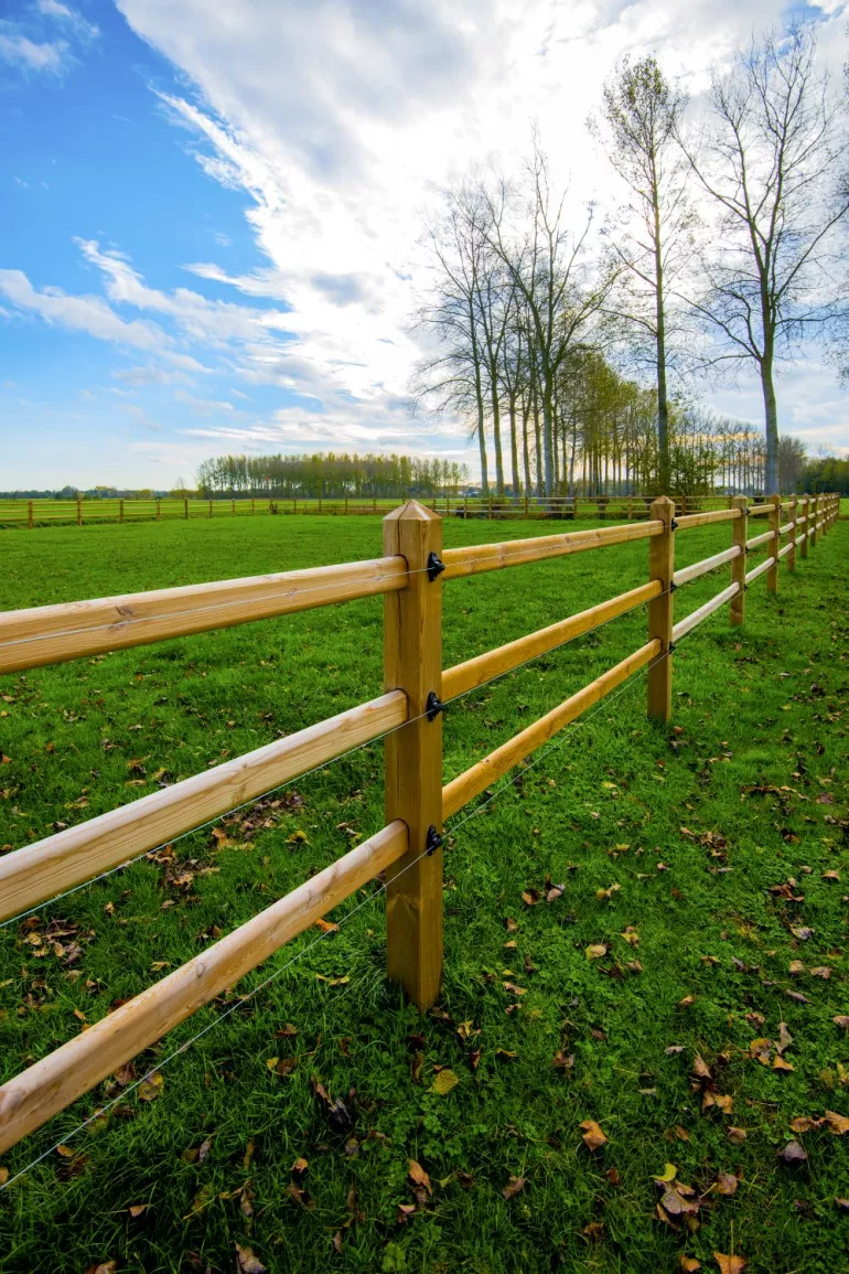 Holzzaun mit drei Stäben, Brettern, die durch die quadratischen Pfosten gleiten, und elektrischen Drähten
