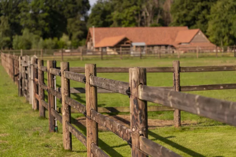 Wooden fences with three rails, electric wires and boards that slide through the round posts