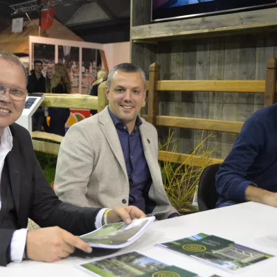 Trois hommes devant des clôtures en bois avec des rails