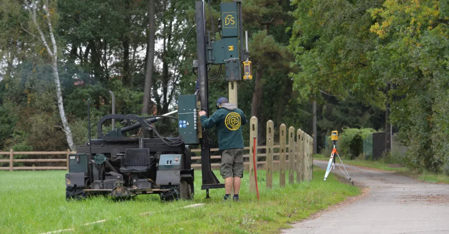 Ein Mann installiert Holzzäune mit einer Pfostenrüttelmaschine